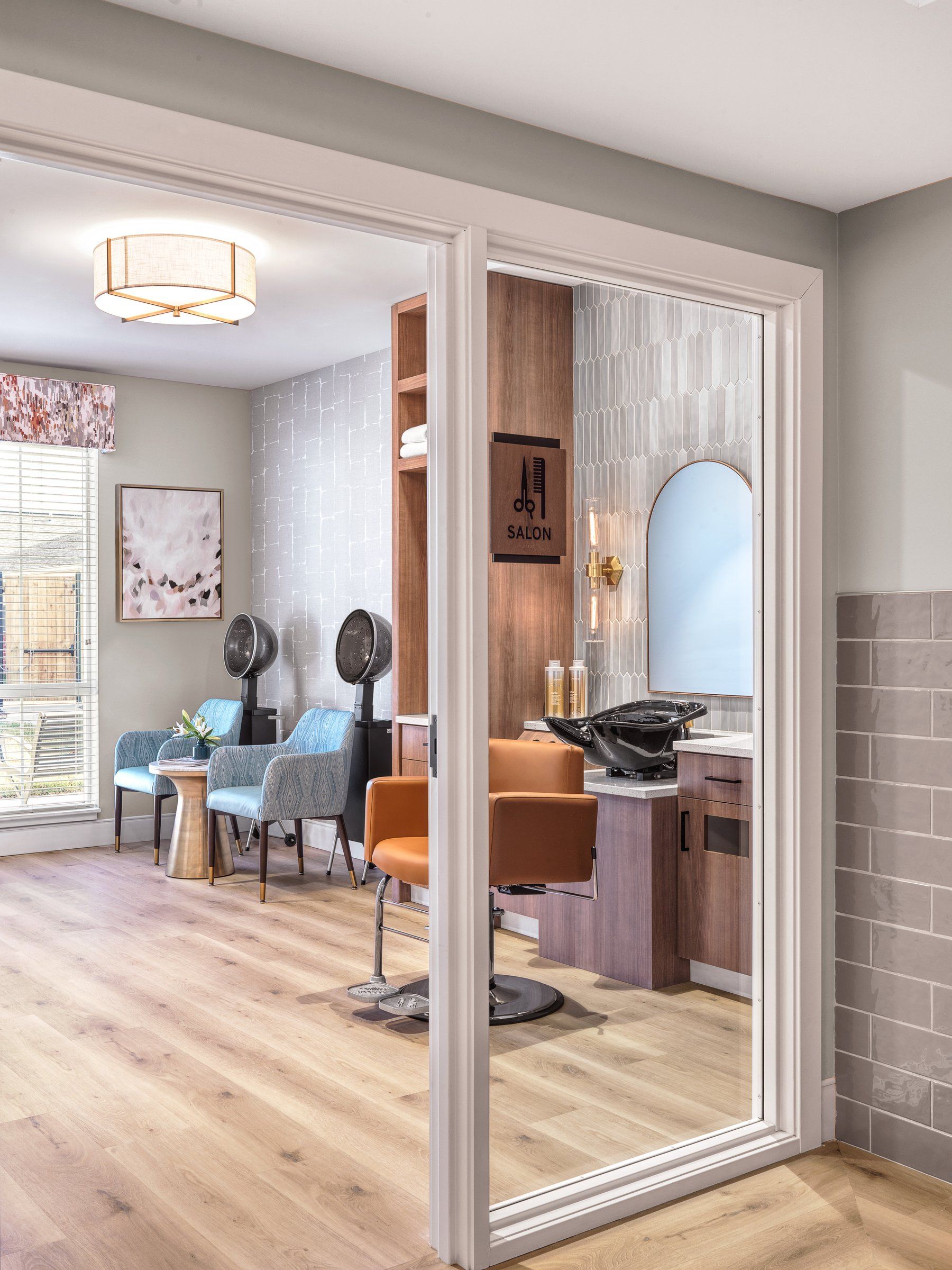 A salon seen through a glass door, finished in wood, tile and soft light