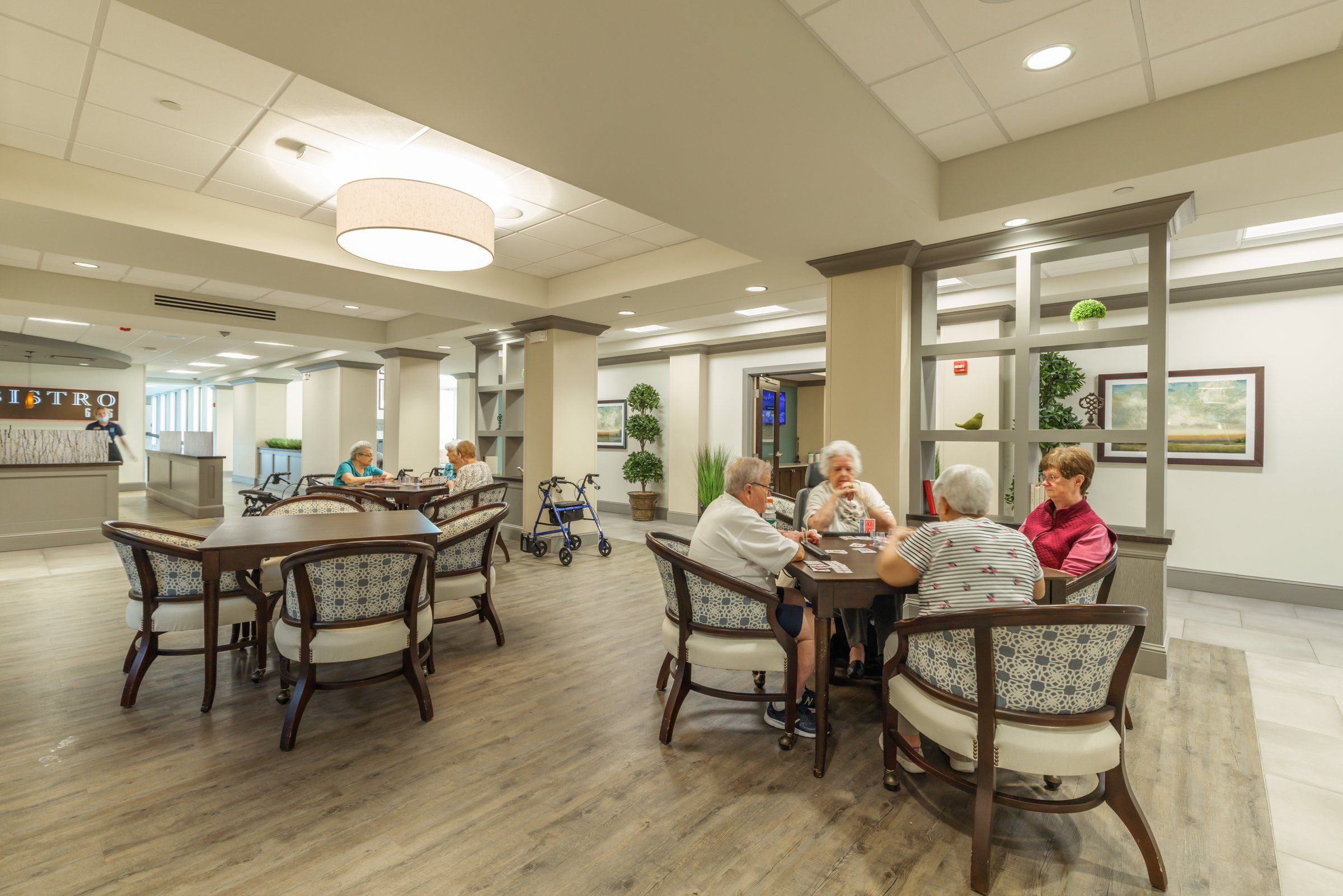 Residents play cards at a table in a bright, open bistro